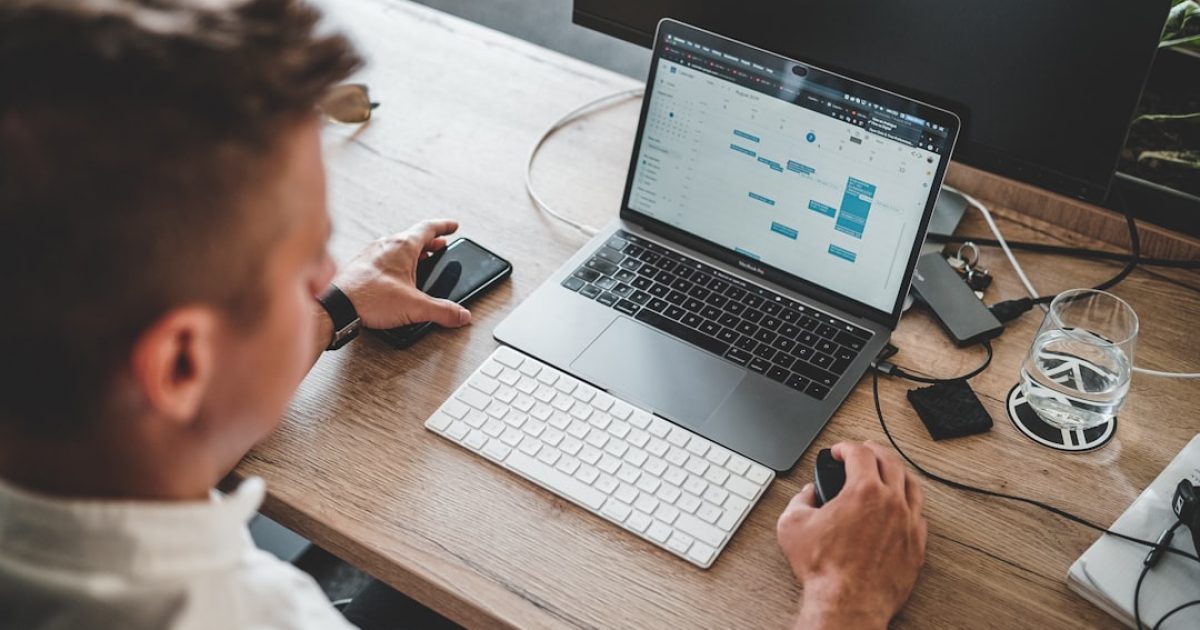 Desenvolvedor a trabalhar num portátil com código PHP no ecrã, mostrando a versão 8.3 e otimizações de performance, num ambiente de escritório moderno.